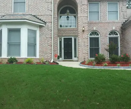 Green front lawn and planting beds at a brick house
