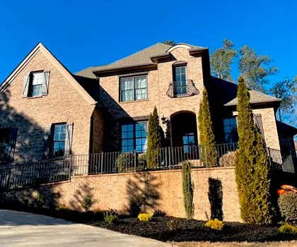 Brick and stone house with new evergreen plantings along the front