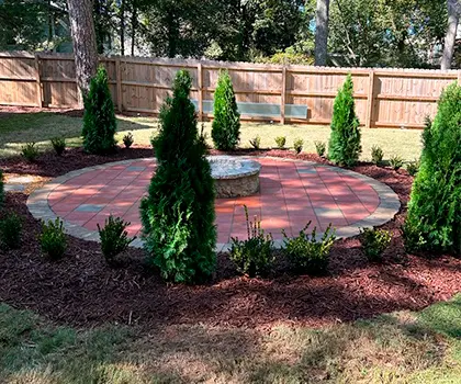 Paver patio with evergreens and shrubs planted around it