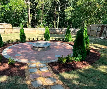 Circular paver patio surrounded by fresh planting beds