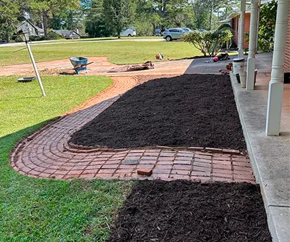 Curved brick paver border along a new mulch bed